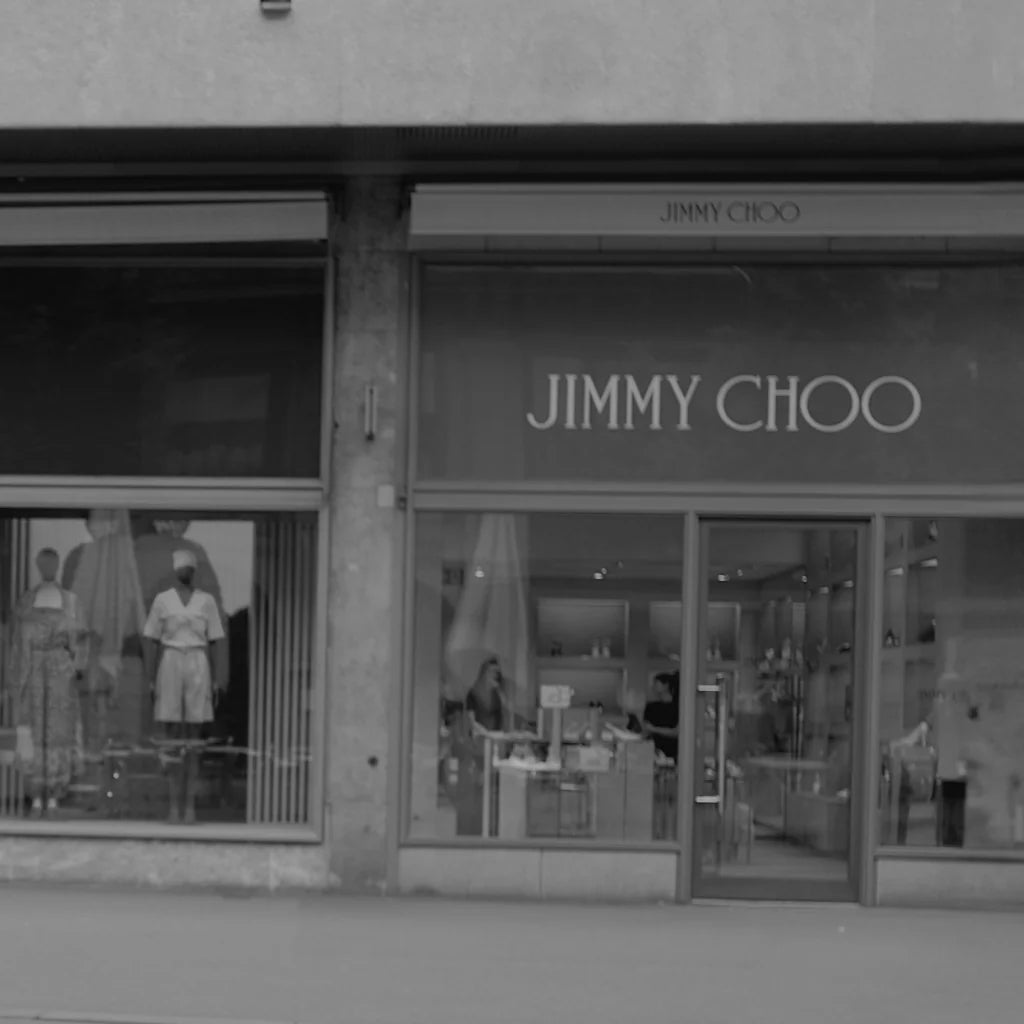 Exterior view of Jimmy Choo luxury fashion boutique with mannequins in the window display and customers inside the store