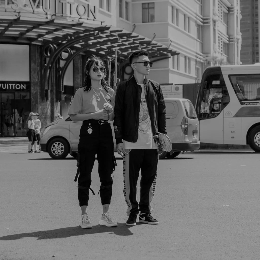 Stylish man and woman wearing casual streetwear standing outside a Louis Vuitton store in an urban setting