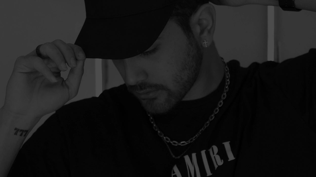 Man wearing an Amiri t-shirt, Nike cap, and silver chain, embodying luxury fashion with an effortless streetwear edge. The black-and-white style highlights the blend of high-end and affordable fashion, perfect for trendsetters in Essex.